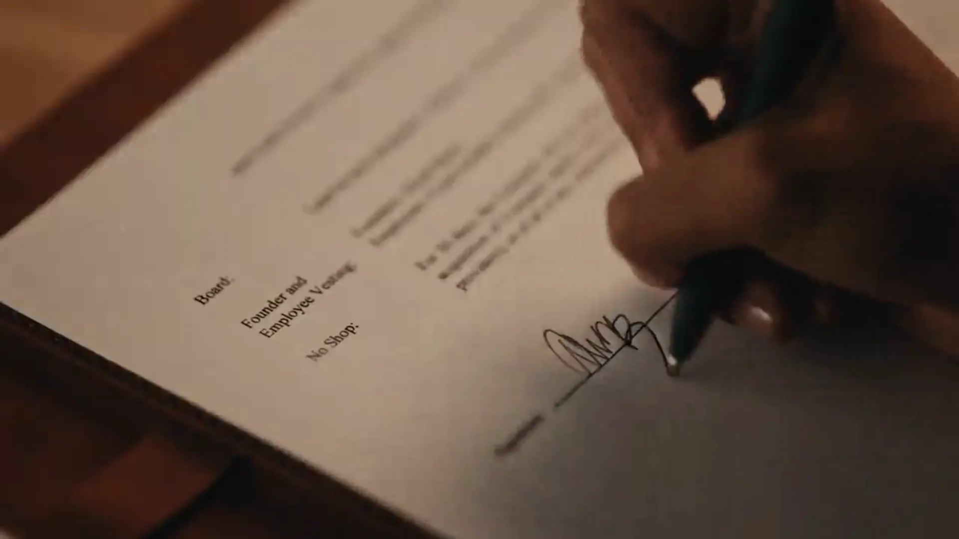 Close-up of a hand signing a term sheet with a blue pen
