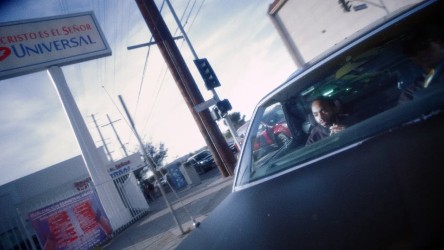 Frame from the Fly Anakin No Dough music video: man in a car window on a street, a Cristo Es el Señor sign above