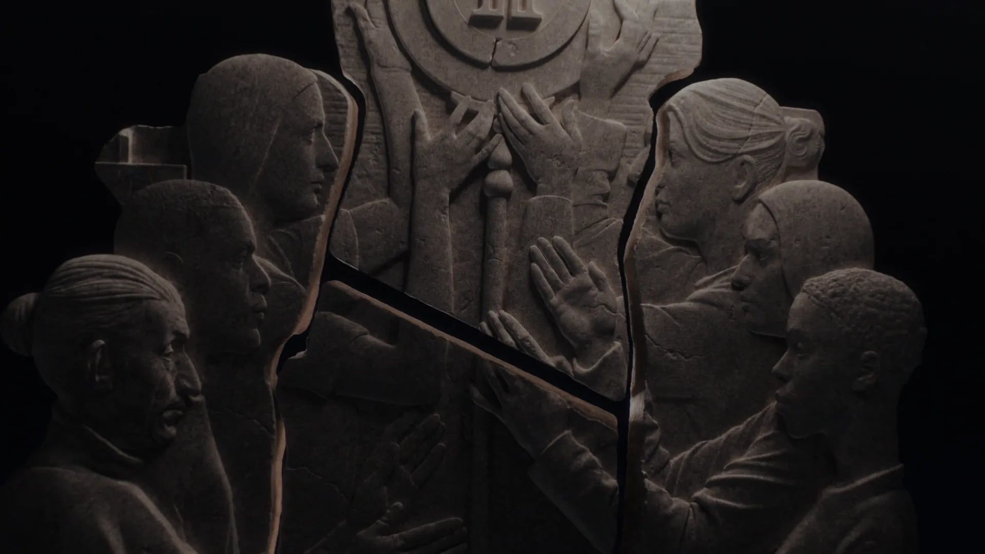 Forum brand identity: stone relief of carved figures with raised hands around a circular emblem, lit in the dark