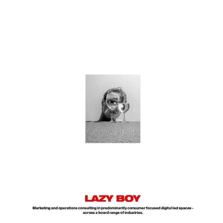 Lazy Boy ad layout: small black and white photo of a man behind two wine glasses above the red LAZY BOY wordmark