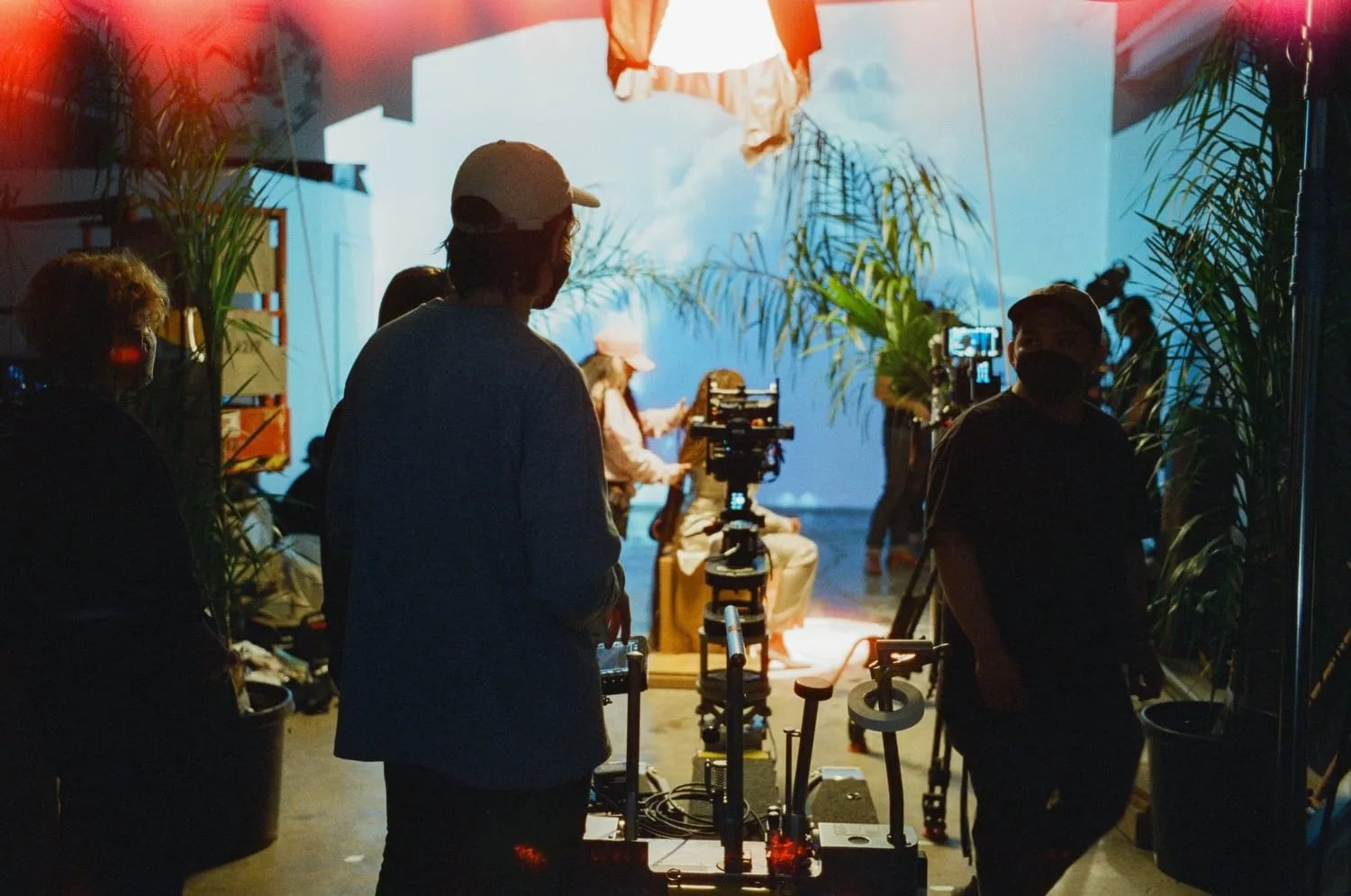 Behind the scenes on the Stoney Creation Repair shoot: crew and camera on a dolly in a studio with palms and a cloud backdrop